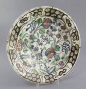 An Iznik pottery dish, Turkey c.1680 - 1720, painted with flowers and foliage within a scroll work