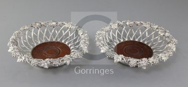 An ornate pair of Victorian silver wirework wine coasters by Edward & John Barnard, with vineous