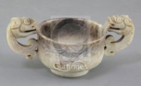 A Chinese cream and black jade two handled cup, 16th/17th century, carved in relief with chi-dragons