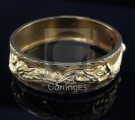 A Chinese high carat gold hinged bangle, with bright cut and applied decoration, character marks