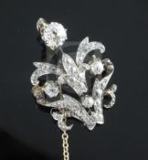 A Victorian style gold and platinum diamond set scrolling pendant brooch, the largest diamond