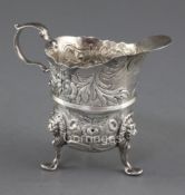 A mid 18th century Irish silver tripod milk jug, by William Townsend? with repousse floral