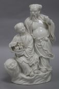 A Chinese blanc de chine group of two deities and a lion, height 23.5cm
