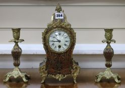 An early 20th century red boullework mantel timepiece, with a pair of similar candlesticks clock