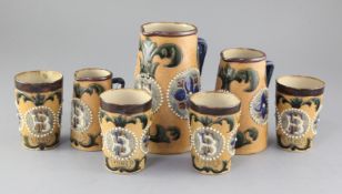 A collection of Fulham pottery stoneware vessels, c.1902, comprising three jugs and four beakers,