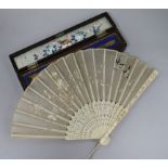 A 19th century Chinese ivory and embroidered silk fan in a lacquer box.