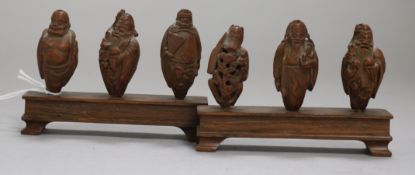 A set of six Chinese peach stones carved as immortals and a monkey, rosewood stands, each approx.