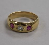 An 18ct gold, three stone ruby and diamond gypsy set ring, size U.