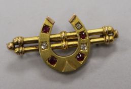 A late Victorian yellow metal, ruby and diamond set horseshoe twin bar brooch, 45mm.