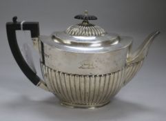 A late Victorian silver teapot, of oval half-reeded form, with ebony handle and finial, crested,