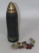 Militaria. A shell casing and Boer War and later Scottish cap badges.