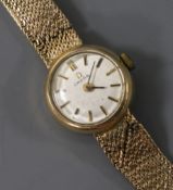 A lady's 9ct gold Omega manual wind wrist watch with an integral 9ct gold bracelet.