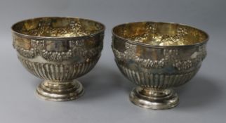 A near pair of silver pedestal rose bowls, half-fluted and embossed with ribbon-tied swags, with