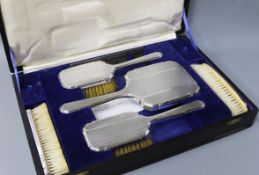 A cased George V Art Deco engine turned silver six piece dressing table set, William Comyns & Sons