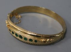 An Edwardian style 9ct gold and emerald hinged bangle.