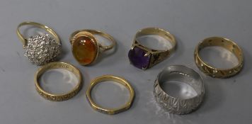 Four various 9ct gold textured rings, one gypsy-set, a 9ct gold and amethyst ring, a similar amber