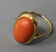 A yellow metal and oval cabochon coral ring, size R.