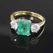 A modern 18ct gold, emerald and diamond three stone ring, the central emerald cut stone flanked by