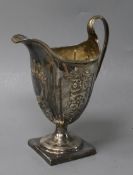 A George III silver helmet-shaped cream jug, embossed and crested, in later fitted case, London