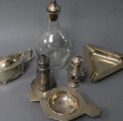 An Art Deco silver tea strainer, a silver ashtray, three silver condiments and a white metal mounted