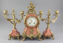 An early 20th century French pink marble clock garniture, with applied shell, scroll and dolphin