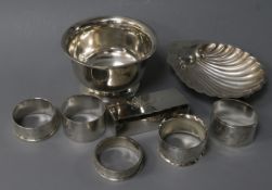 A silver shell butter dish, a silver bowl, five assorted silver napkin rings and a silver stamp