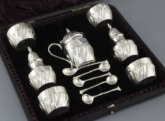 A cased Victorian repousse silver seven piece condiment set by James Deakin & Sons Ltd, with five