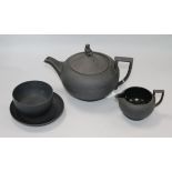 A black basalt teapot, a cream jug, a saucer and a bowl