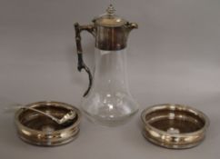 A silver plate mounted claret jug, a pair of silver plated wine coasters and a plated sauce ladle.