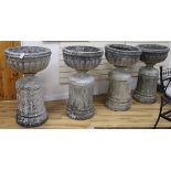 A set of four large cup shaped garden urns on fluted plinths (one a.f.)