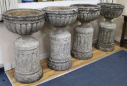 A set of four large cup shaped garden urns on fluted plinths W.55cm approx.(one a.f.)