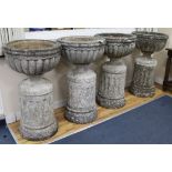 A set of four large cup shaped garden urns on fluted plinths W.55cm approx.(one a.f.)