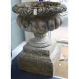 A pair of reconstituted stone garden urns, of campana shape, raised on stepped plinths