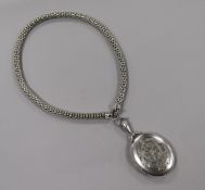 An engraved white metal oval locket decorated with bird and monograms, on a fancy link white metal