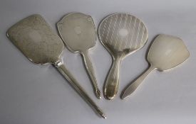 Four assorted 20th century silver hand mirrors including three engine turned and one with foliate