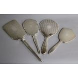 Four assorted 20th century silver hand mirrors including three engine turned and one with foliate