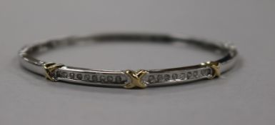 A modern 14ct white gold and channel set diamond hinged bangle, with yellow gold "x" motifs, gross