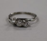 A 1940's white metal and three stone diamond crossover ring, size L.