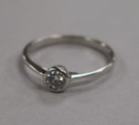 An 18ct white gold and collet set solitaire diamond ring, size N.