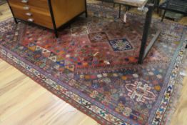 A Persian faded cream and red ground carpet 284cm x 196cm