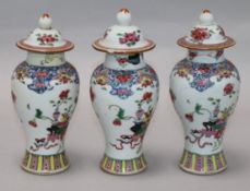 A set of three Chinese Qianlong period famille rose vases and covers (a.f.)