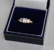 An emerald-cut diamond three-stone ring, 18ct yellow gold shank, size L.