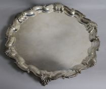 A silver salver, with shell, scroll and piecrust edge raised on three claw and ball feet,