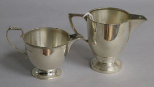 A George VI Art Deco silver cream jug, Birmingham, 1941 and a George V smaller silver cream jug,
