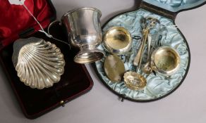 A George V silver scallop butter dish, cased, a later christening mug, a pair of tongs and sundry