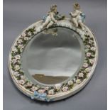 A ceramic floral and putti encrusted wall mirror length 42cm