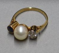 An 18ct yellow gold, cultured pearl, sapphire and diamond three-stone ring, size L.