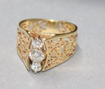 A pierced yellow metal and three stone diamond dress ring, size L.