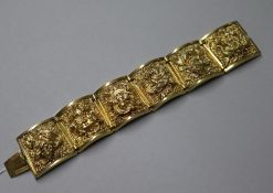 A Far Eastern yellow metal sectional bracelet fitted six figure-embossed tapered panels, 18cm.