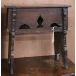 A 17th century oak Gothic style boarded stool, on trestle supports W.53cm